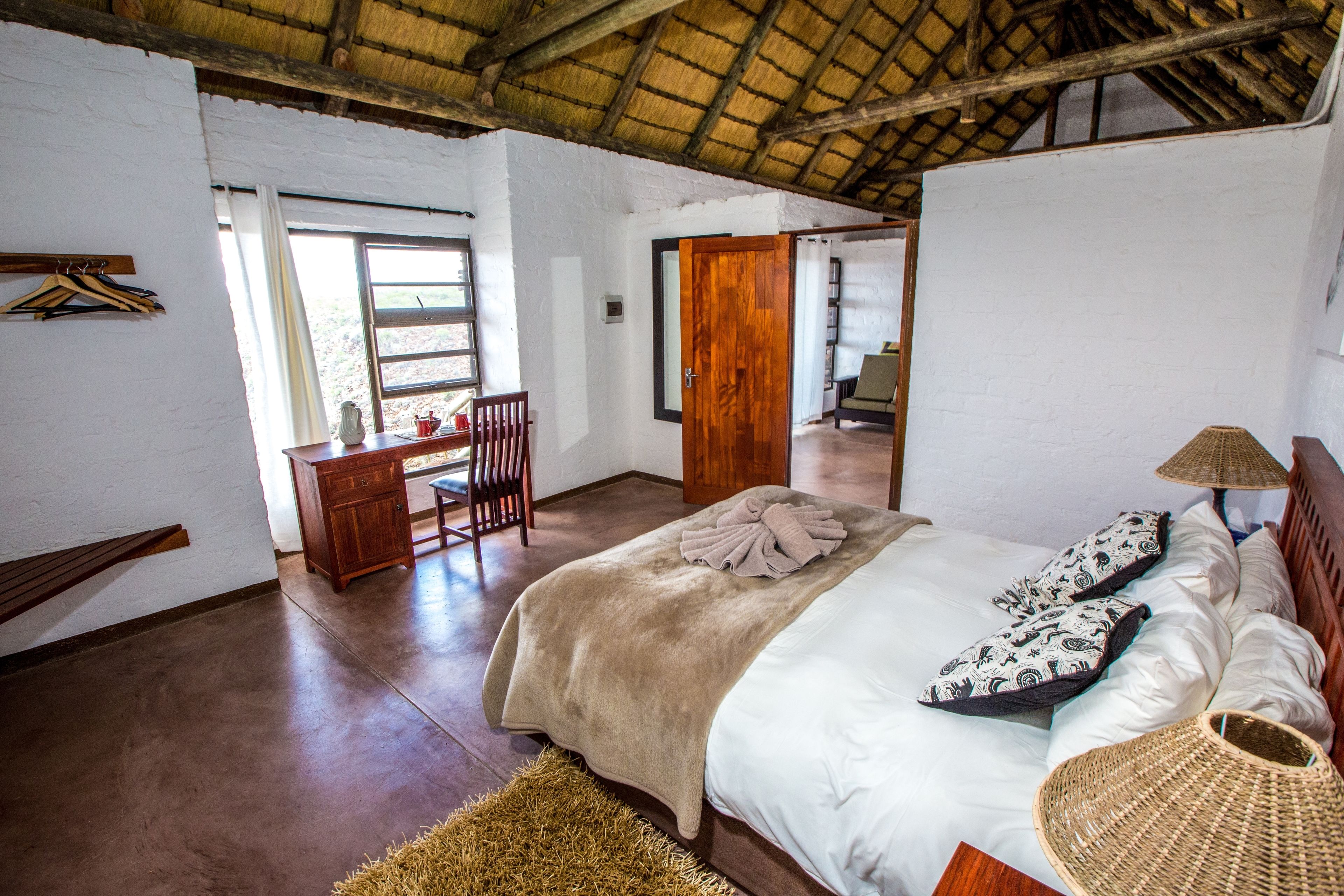 A bedroom with a bed, wooden furniture, a desk, and a chair.