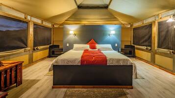 A tent-style room with a bed, two nightstands, and a wooden bench.