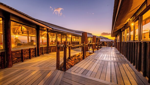 A wooden deck with glass windows leading to a building, suggesting a resort or hotel setting. - Moon Mountain Lodge (Solitaire)