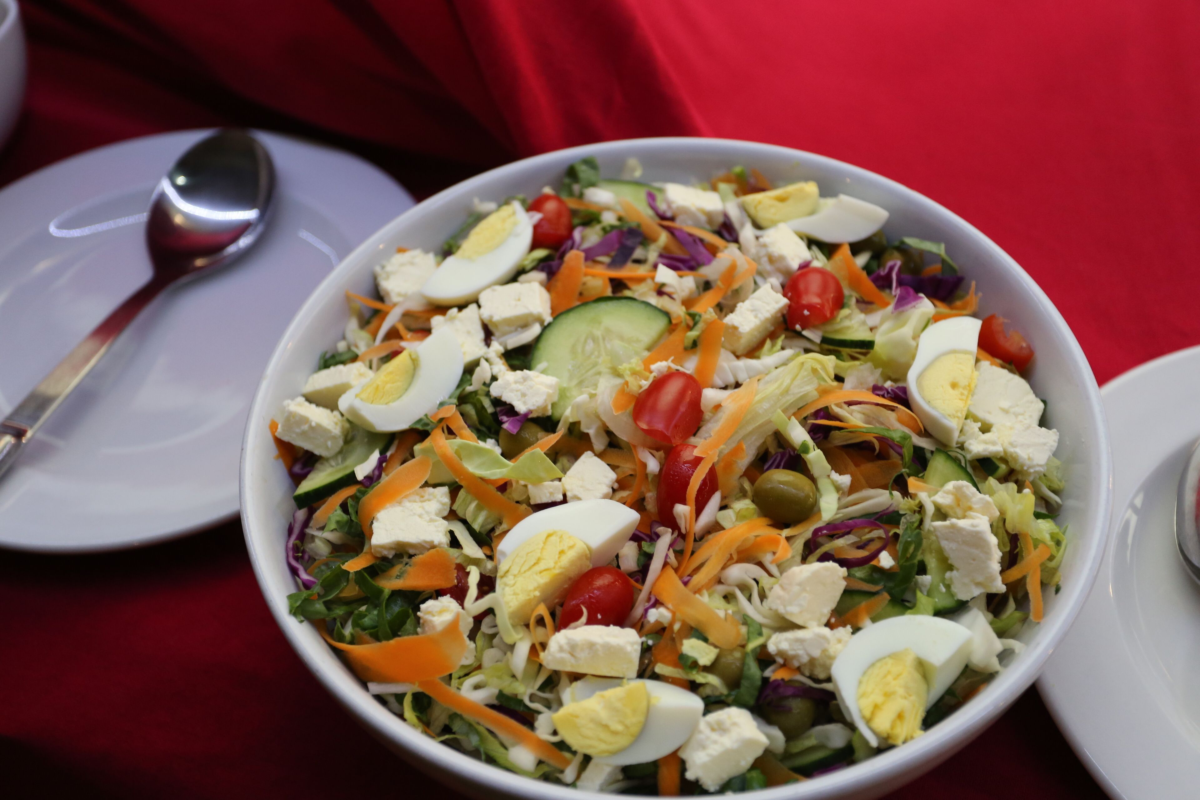 Eine Schüssel mit Salat, verschiedenen Gemüsesorten und Eiern auf einem weißen Teller.