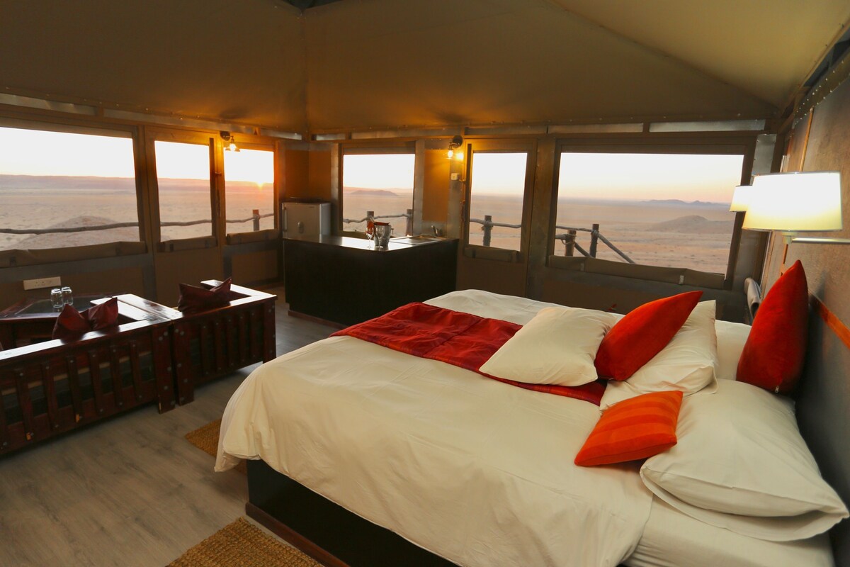 A bedroom with a bed, bedside table, and a desk with a chair.