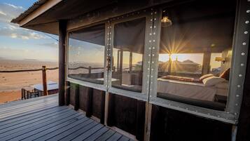 Enjoy breathtaking views of the desert landscape from this room's large window, featuring a comfortable bed and a cozy seating area.