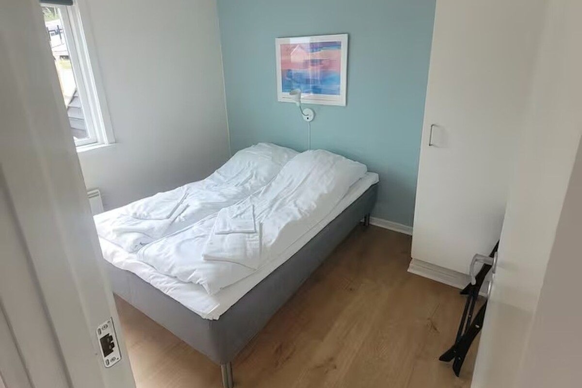 A bedroom with a bed, a window, and a ceiling light.