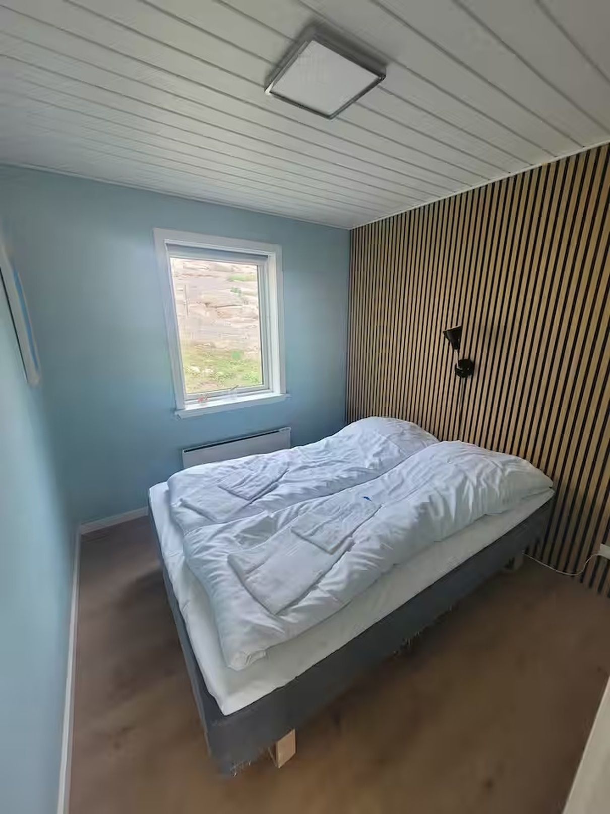Un dormitorio con cama, ventana y radiador.