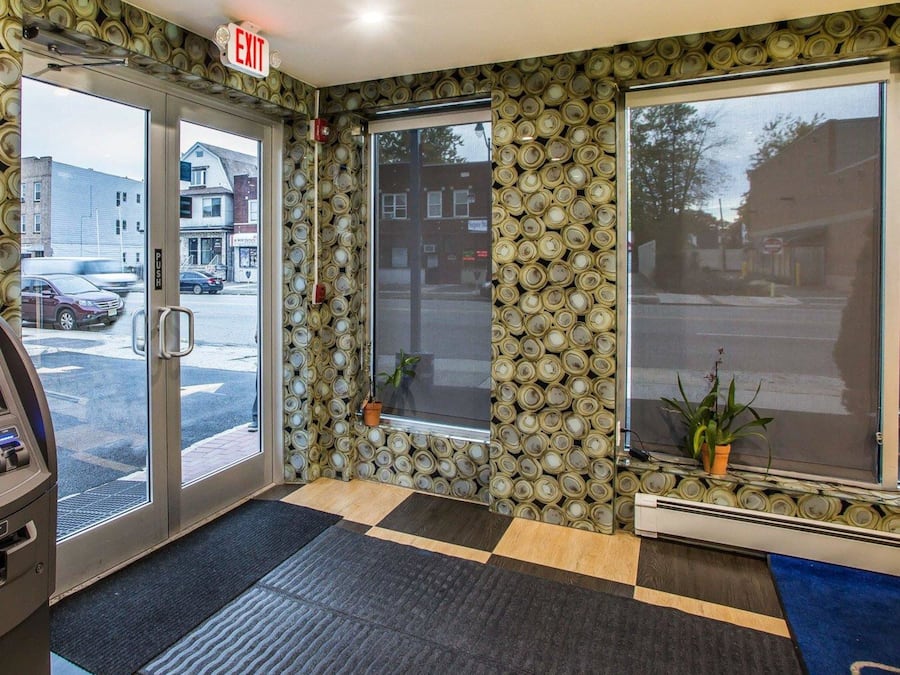 A hotel lobby with a check-in counter, a reception desk, and a large window offering a view of the street.