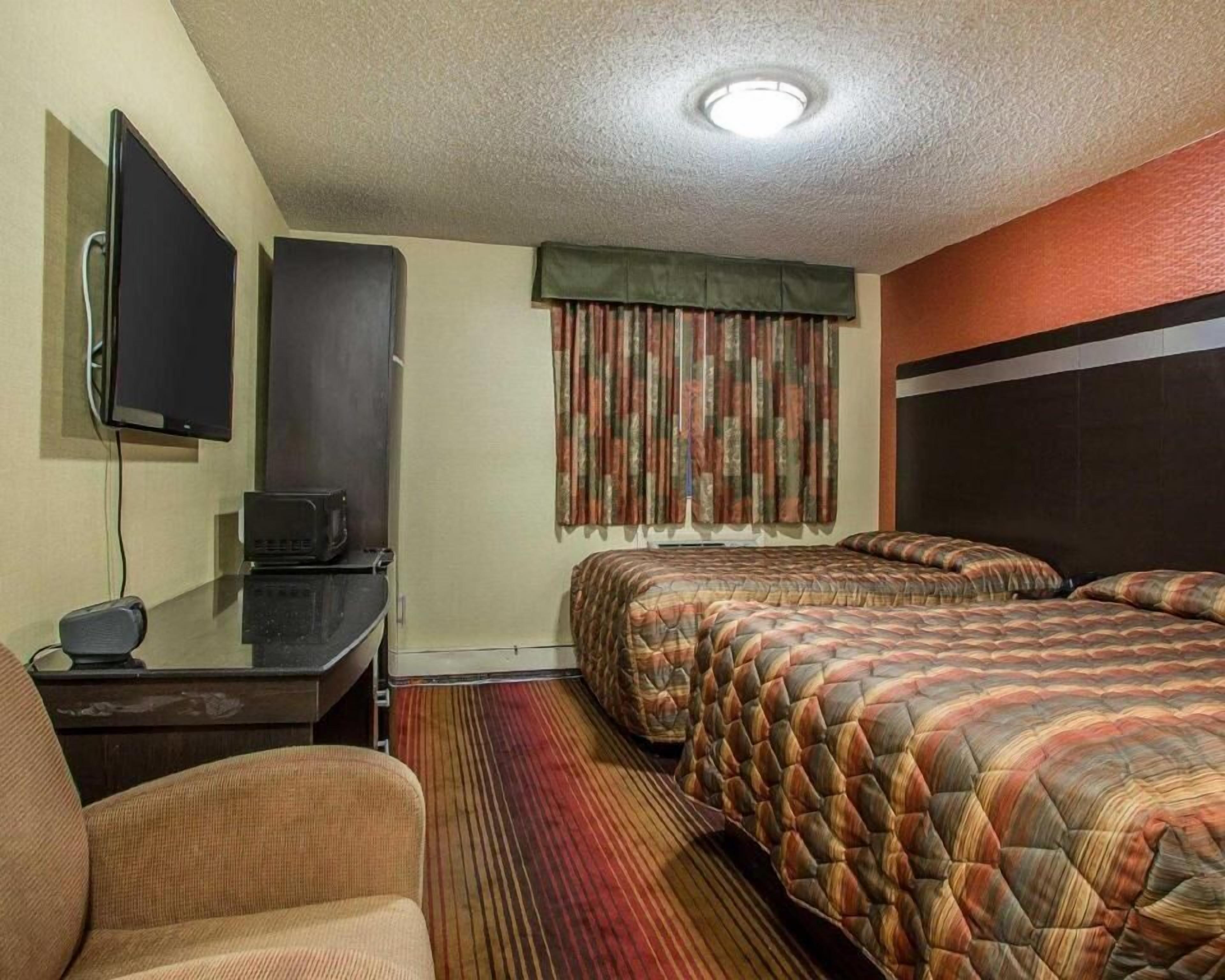 Una habitación de hotel con dos camas, un escritorio con televisor y una silla.