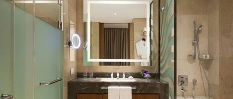 A modern bathroom with a vanity, a large mirror, a ring light, a shower, and a bathtub.