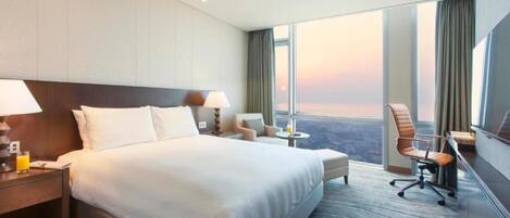 Habitación de hotel con una cama grande, un escritorio, una silla y vistas a la ciudad.