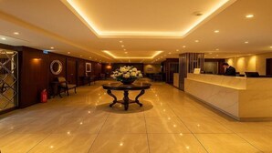 A hotel lobby with a reception desk, a round table with flowers, and a fire extinguisher. - Taxim Express (Istanbul)