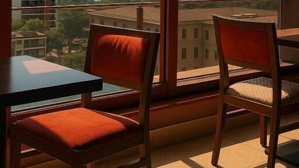 A balcony with two chairs and a table, overlooking a cityscape with buildings and a body of water. - Taxim Express (Istanbul)