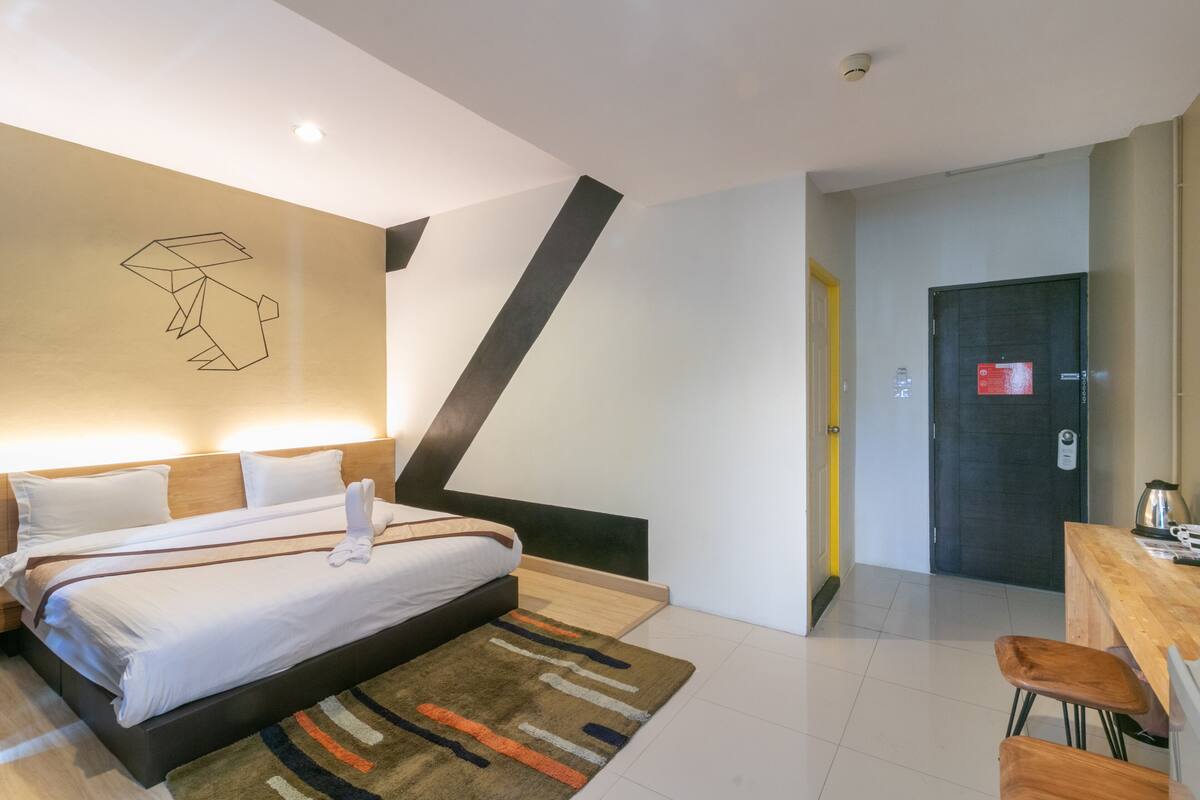 A modern hotel room with a large bed, a desk, and a chair.