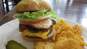 Un plato con una hamburguesa, papas fritas y un pepinillo.