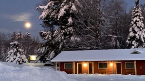 A snow-covered cabin with a wooden exterior and a single visible door.