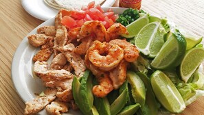 A plate with grilled shrimp, sliced avocado, lime wedges, and diced tomatoes. - North Creek Lodge at Gore Mountain (North Creek)