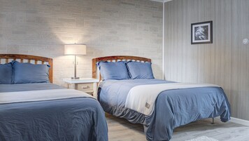 A bedroom with two beds, a nightstand, a lamp, and a framed picture on the wall.