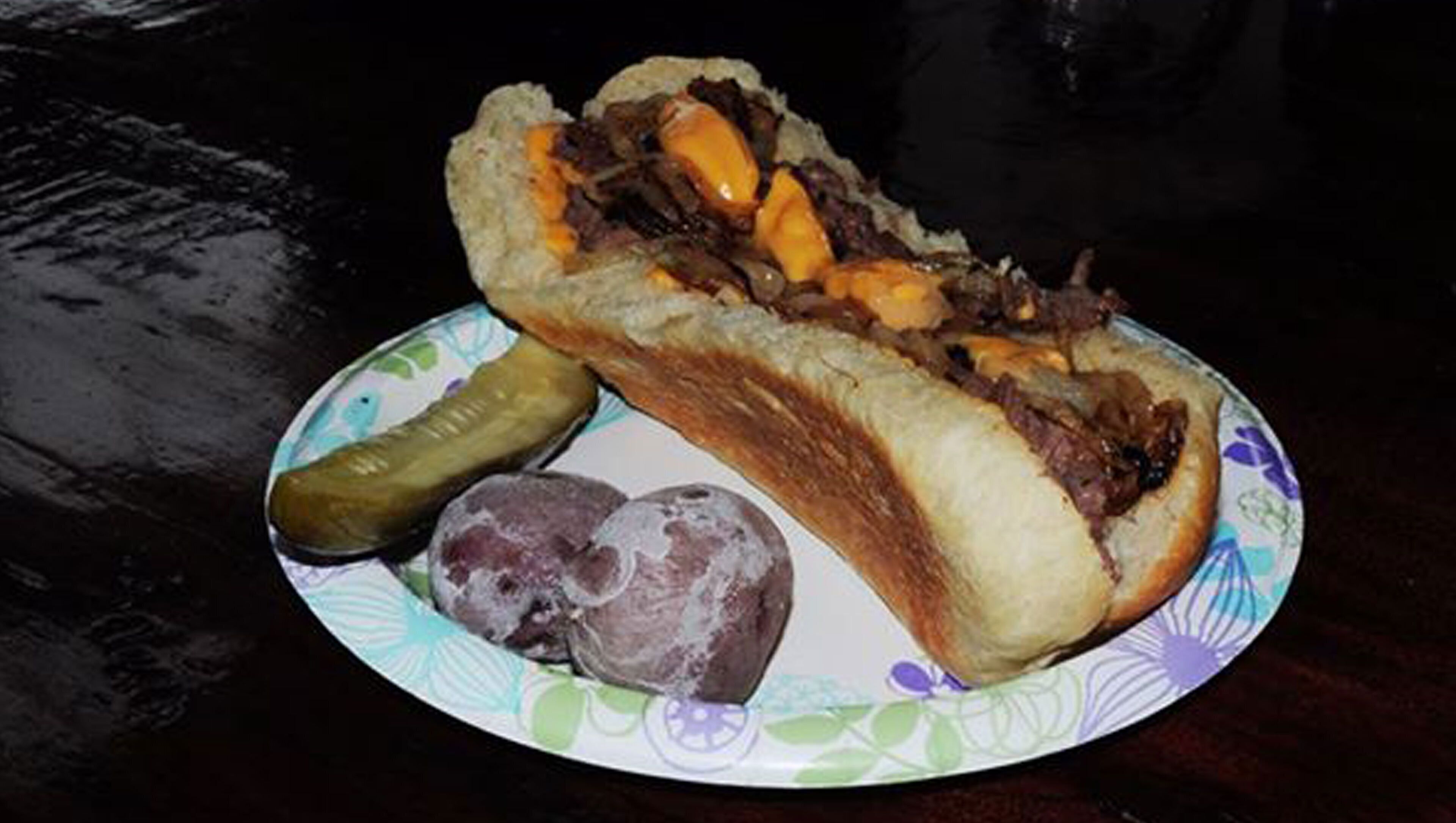Un piatto con un panino, un cetriolo sottaceto e una patata.