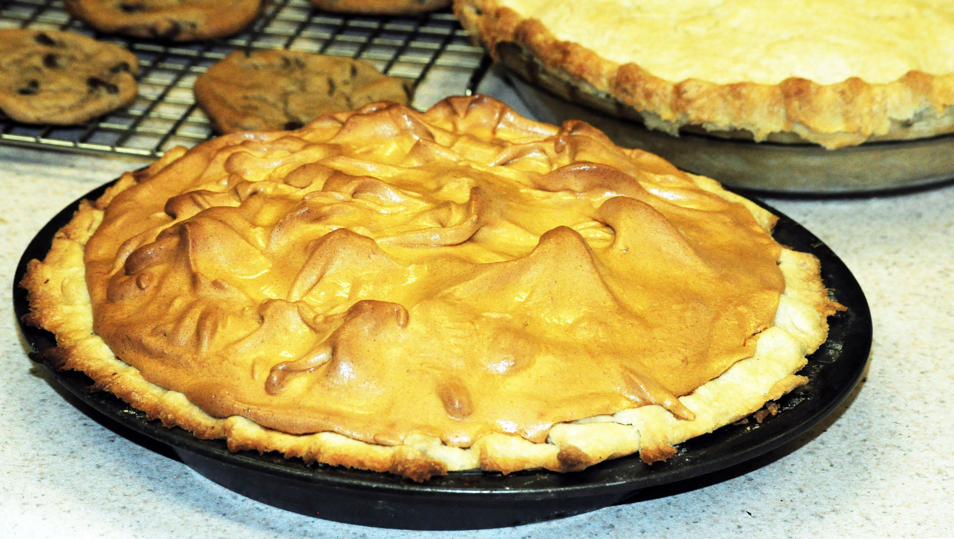 A pie with a golden-brown crust on a black plate.