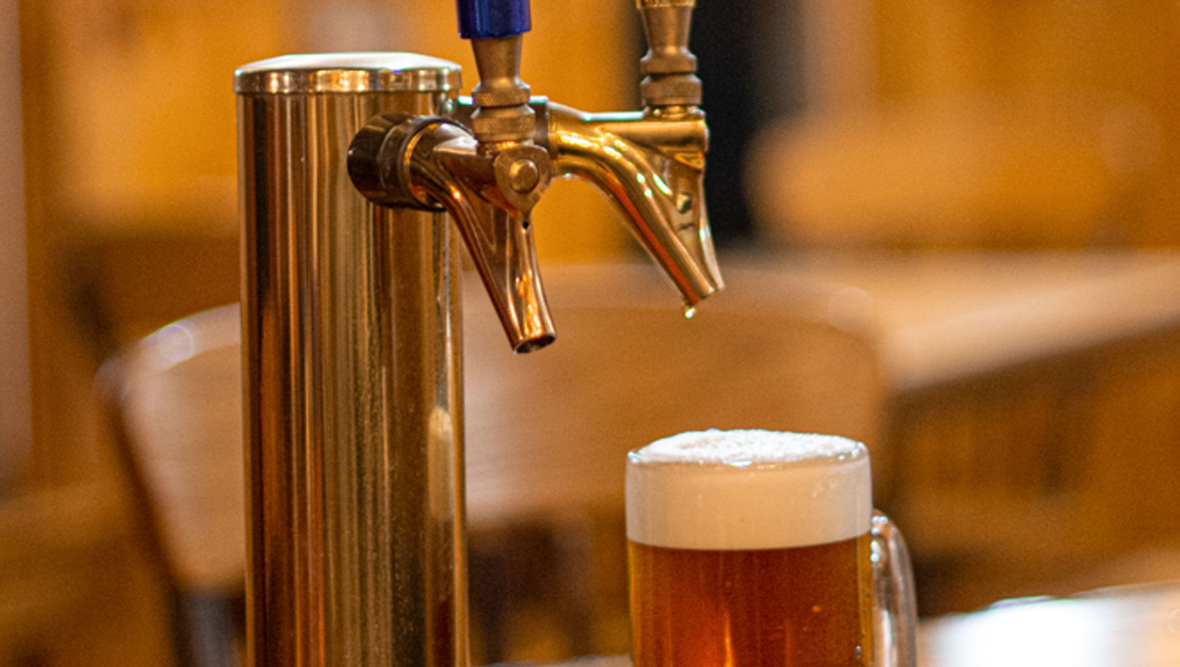 A tap with beer flowing into a glass.