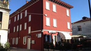 A red building with a sign reading "ottaria" on the ground floor, suggesting a restaurant or cafe. - Venice Apartments Dante (Mestre)