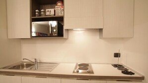 A compact kitchen with a sink, stove, and storage cabinets. - Venice Apartments Dante (Mestre)