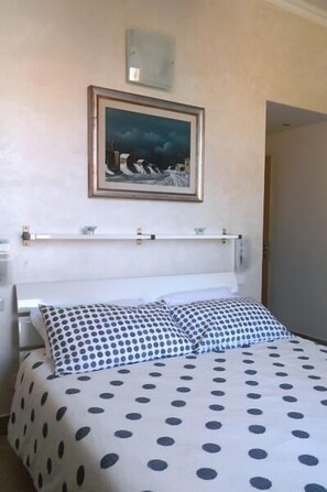 A bed with a polka dot bedspread, a white headboard, and a framed picture above the bed. - Agli Horti Sallustiani bed & breakfast (Rome)