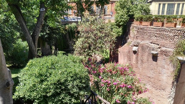 A garden with a brick wall, trees, and flowering bushes. - Agli Horti Sallustiani bed & breakfast (Rome)