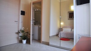 A hotel room with a sliding door leading to a bathroom, a bed with a red rug, and a TV mounted on the wall. - Agli Horti Sallustiani bed & breakfast (Rome)