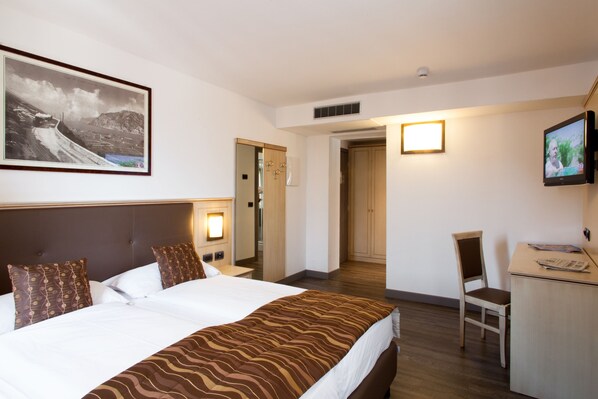 Habitació d'hotel amb un llit gran, una taula de treball, una cadira, una televisió i un quadre al mur.