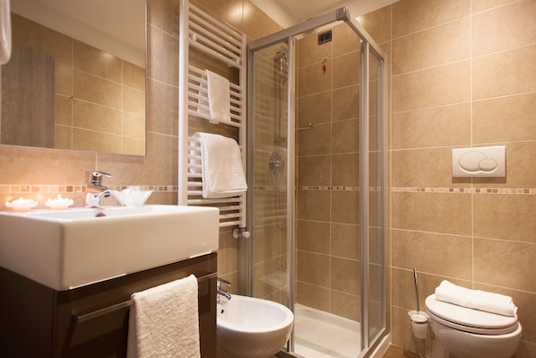 Un baño moderno con ducha envuelta en vidrio, un lavamanos y un inodoro.