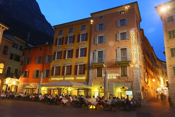 Ein Hotel mit verschiedenen Gastronomieangeboten, darunter ein Restaurant und eine Pizzeria, und einem sichtbaren Außenbereich mit Sitzgelegenheiten.