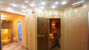 Un sauna de madera con puerta de vidrio, un banco y una vela encendida.