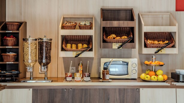 A breakfast buffet area with various food items and condiments. - ACE Hôtel Châteauroux Déols (Deols)