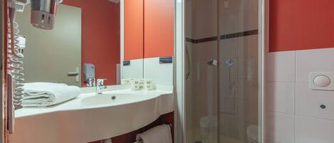 Une salle de bain avec un lavabo blanc, un miroir et une douche à parois de verre.