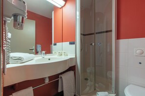 Une salle de bain avec un lavabo blanc, un miroir et une douche à parois de verre.