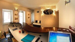 A modern hotel room with a curved desk, a comfortable seating area with a sofa, a large world map on the wall, and a computer on the desk. - Smart Suite & Apartments (Santa Teresa di Gallura)