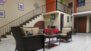 A lobby with wicker furniture, a staircase, and a red tablecloth.