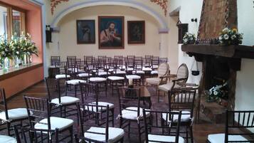 A church interior with rows of wooden chairs, a wooden altar, and religious paintings on the walls.