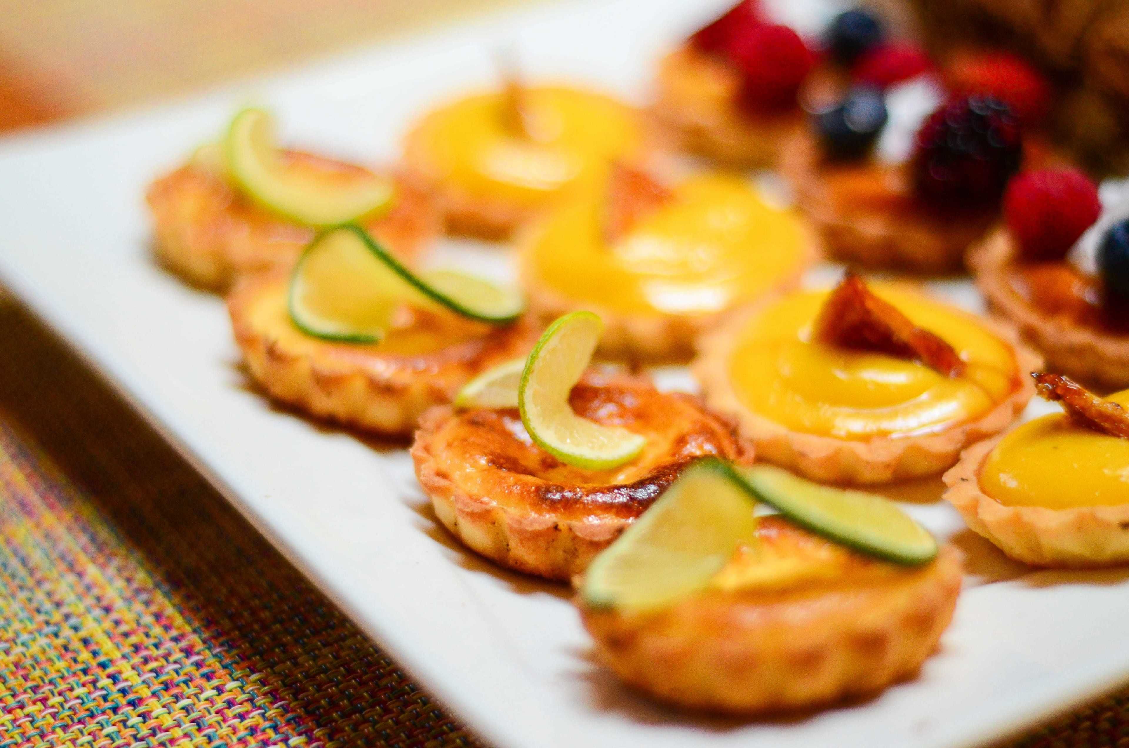 A plate of mini quiches with fruit toppings.