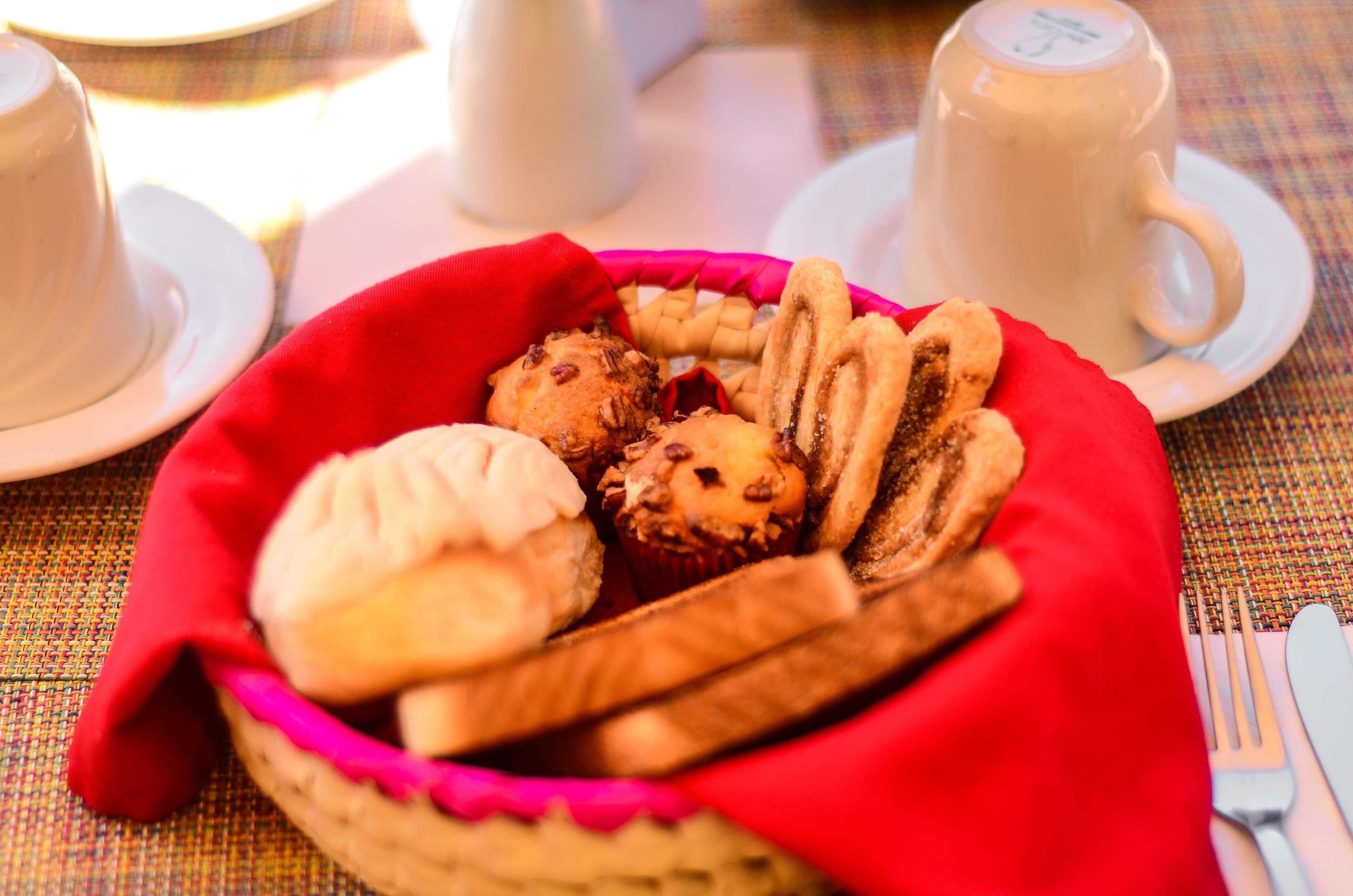 A basket of pastries and cookies on a table with a white cup and saucer.