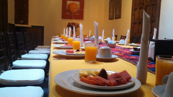 Un bufé de desayuno con platos de fruta, jugo y servilletas blancas.
