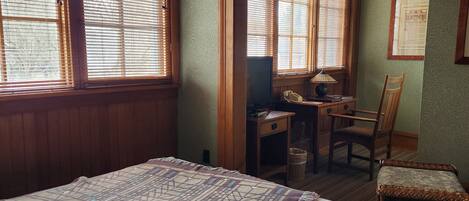 A room with a bed, a desk, a chair, and a window with blinds.