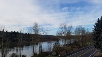 A road with a guardrail, a lake, and trees.