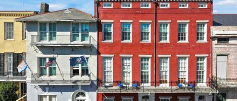 A row of three-story buildings with a red facade and white trim, featuring multiple windows and balconies.