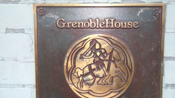A plaque with the text "GrenobleHouse" and "329 Rue Dauphine" on a brick wall. - Grenoble House (New Orleans)