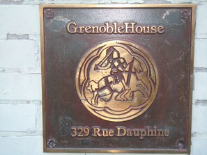 Uma placa com o texto "GrenobleHouse" e "329 Rue Dauphine" em uma parede de tijolos.