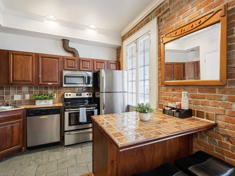 Una cocina con armarios de madera, electrodomésticos de acero inoxidable, una isla con azulejos y una barra para café.