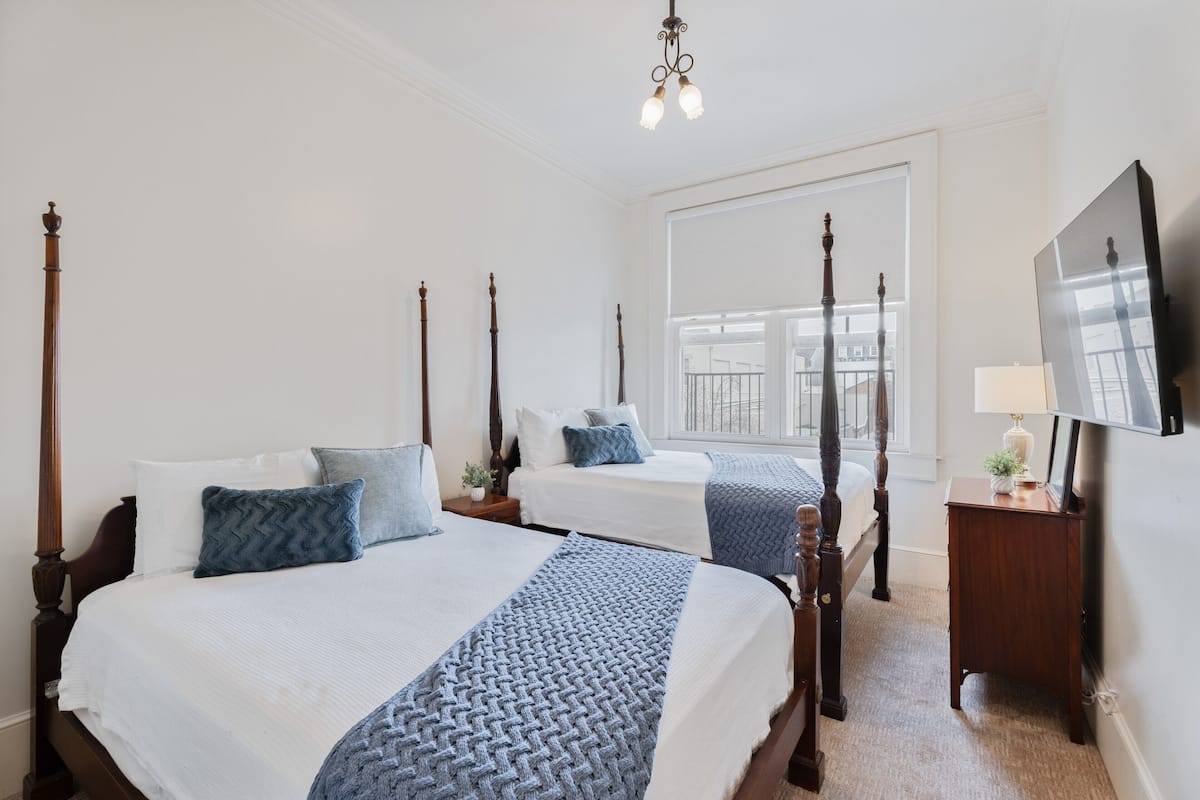 A hotel room with two beds, a large window, a television, and a nightstand.