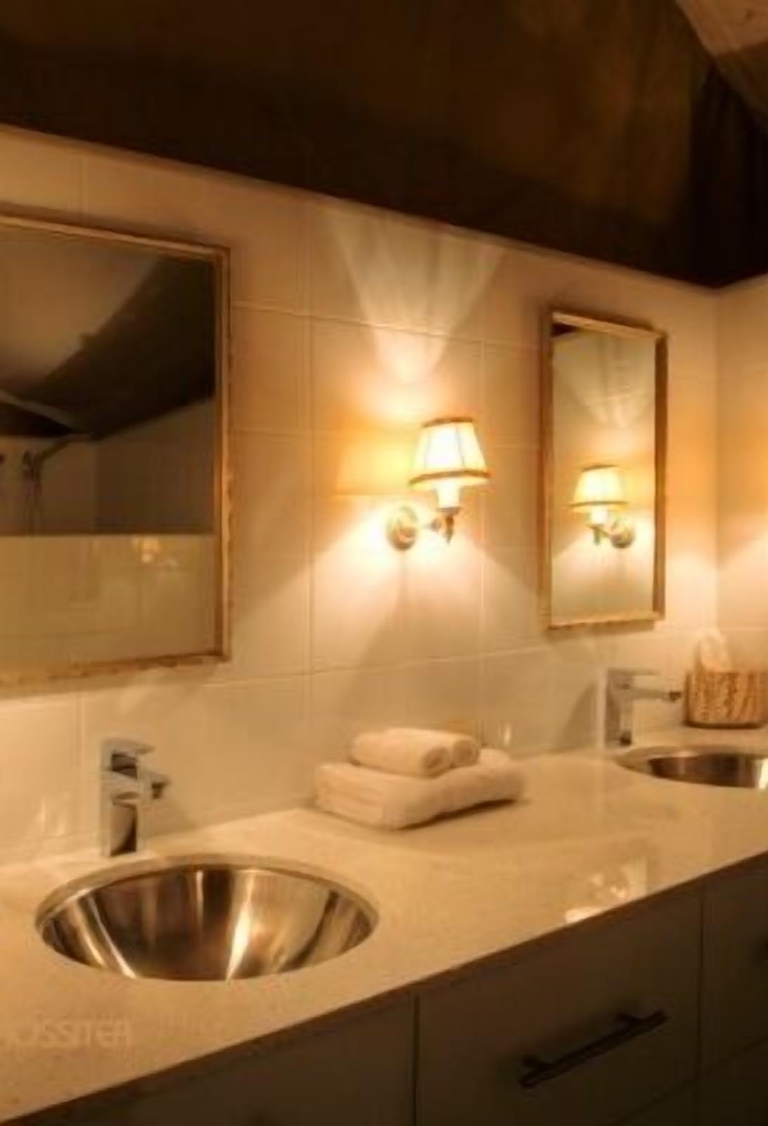 Un baño con lavamanos, espejo y dos luces en la pared.