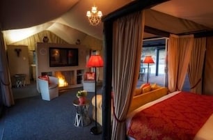 A spacious bedroom with a large bed, a fireplace, and a view of the outdoors.