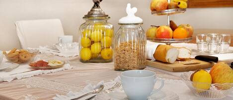 A breakfast table with various food items, including fruits, bread, and a cup.